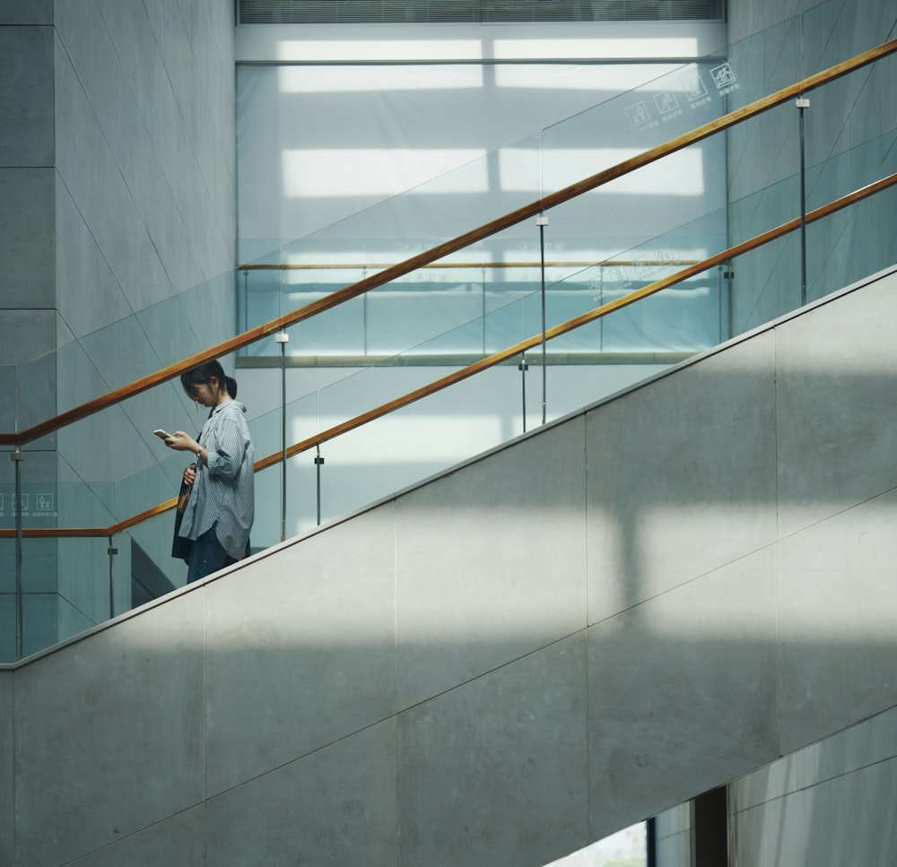 a woman standing on a stair case looking at her cell phone