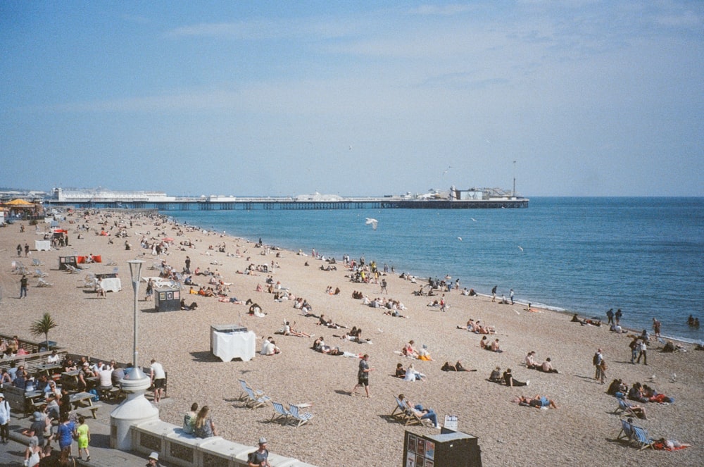 a crowded beach with a pier in the background