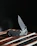 A close-up of a sleek pocket knife resting on a wooden table.