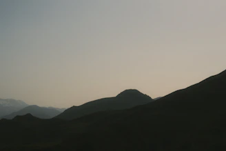 Minimalist desert mountain silhouette in muted gold tones against a near-black textured backdrop