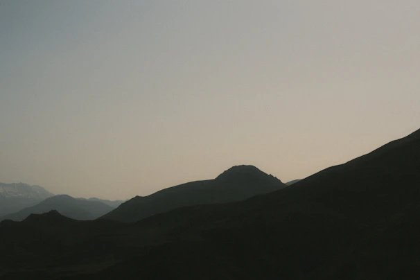 Minimalist desert mountain silhouette in muted gold tones against a near-black textured backdrop