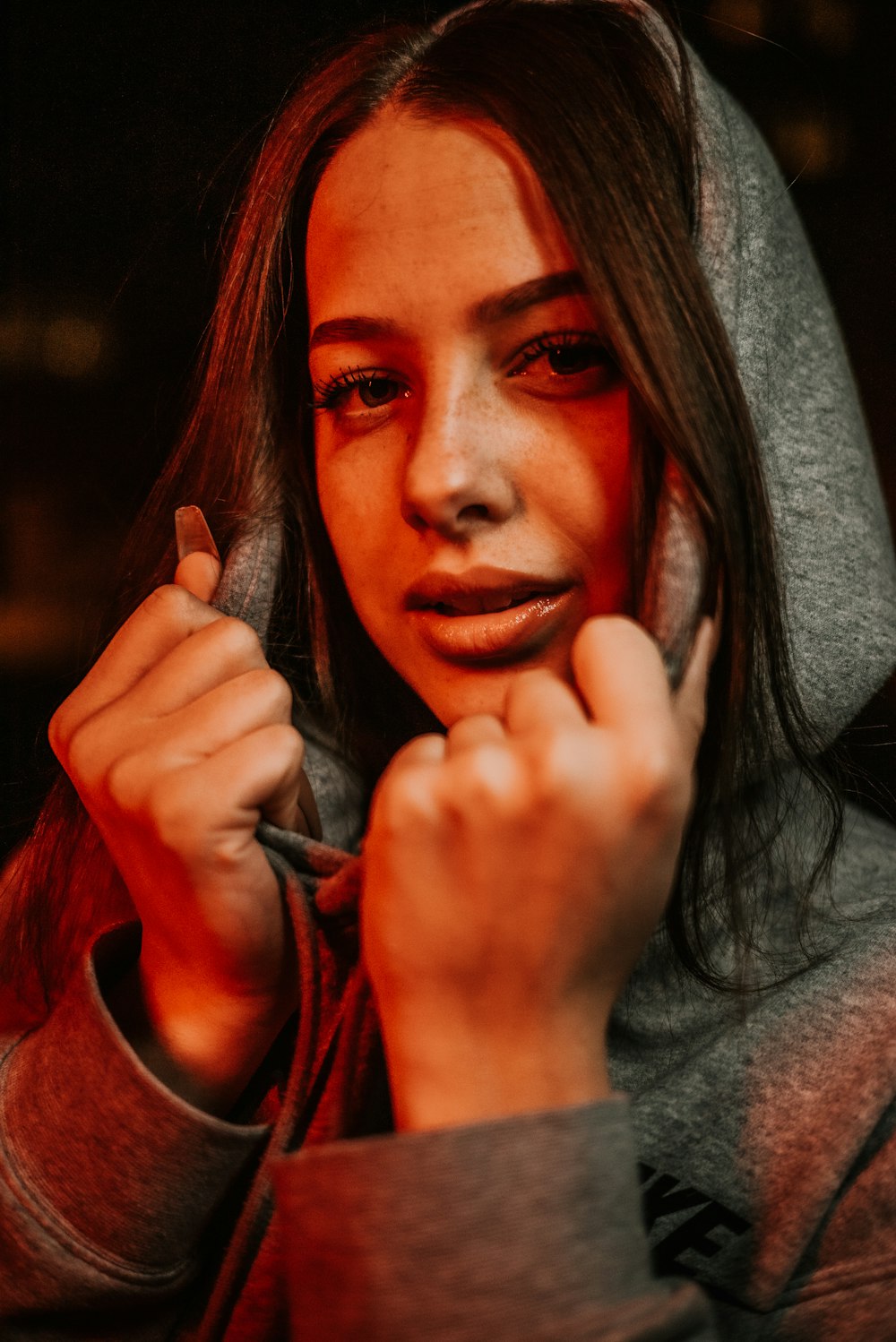 a woman in a hoodie holding a cell phone to her ear