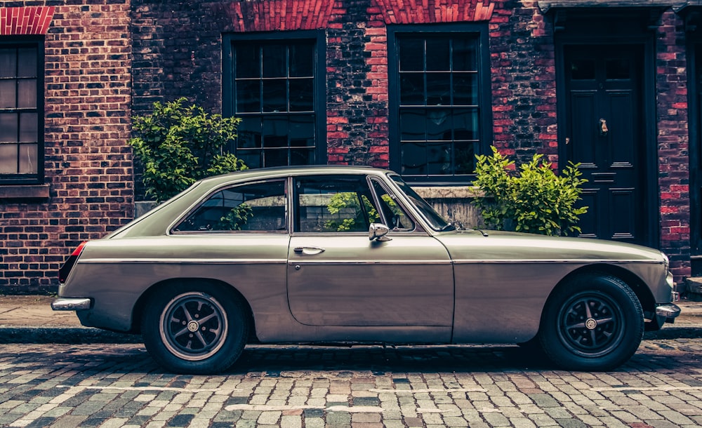 an old car is parked in front of a brick building