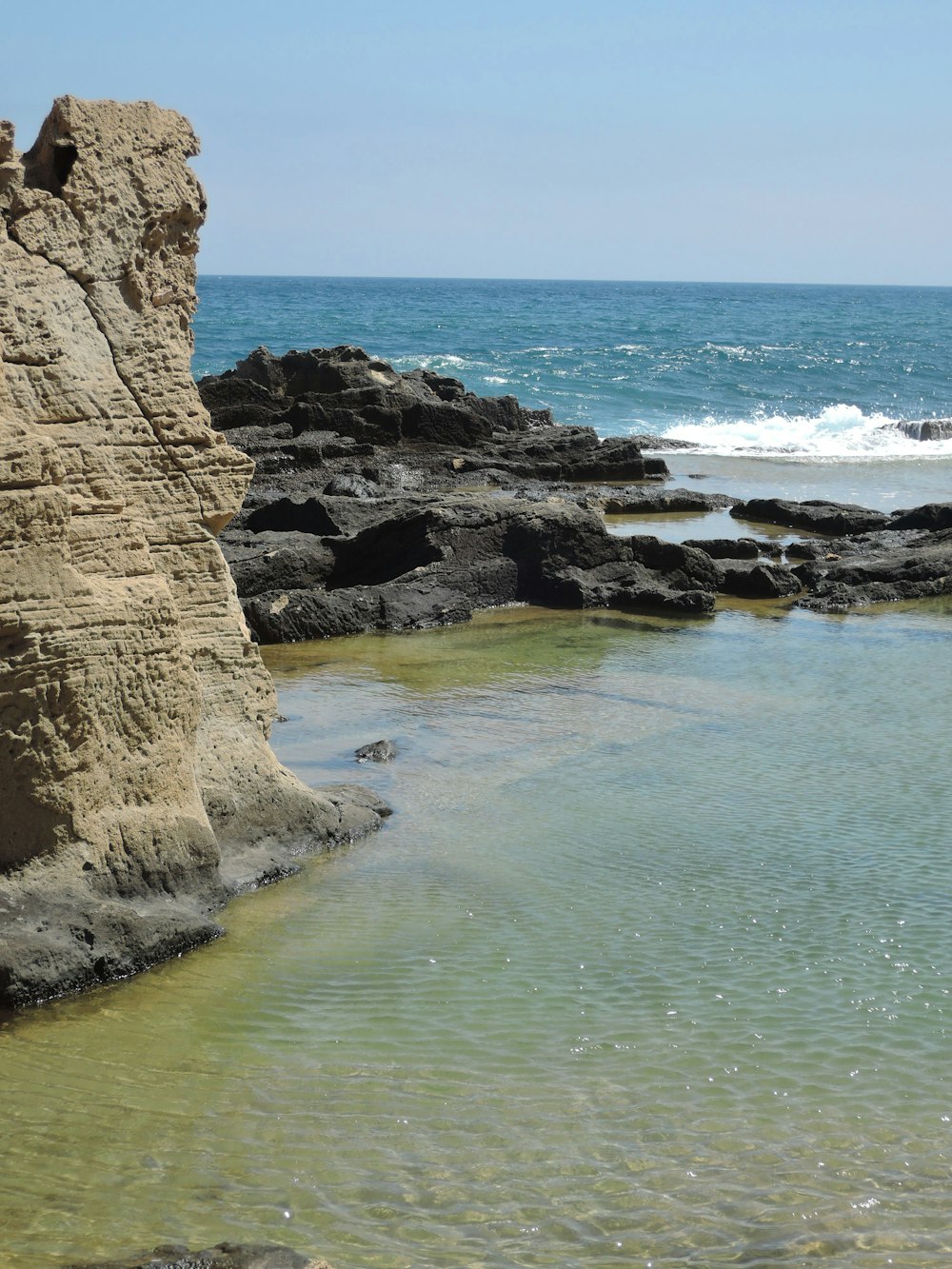 a body of water with rocks in the background