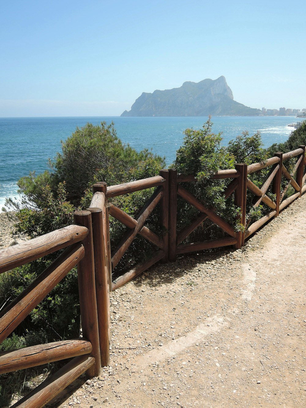 a wooden fence on the side of a hill next to the ocean