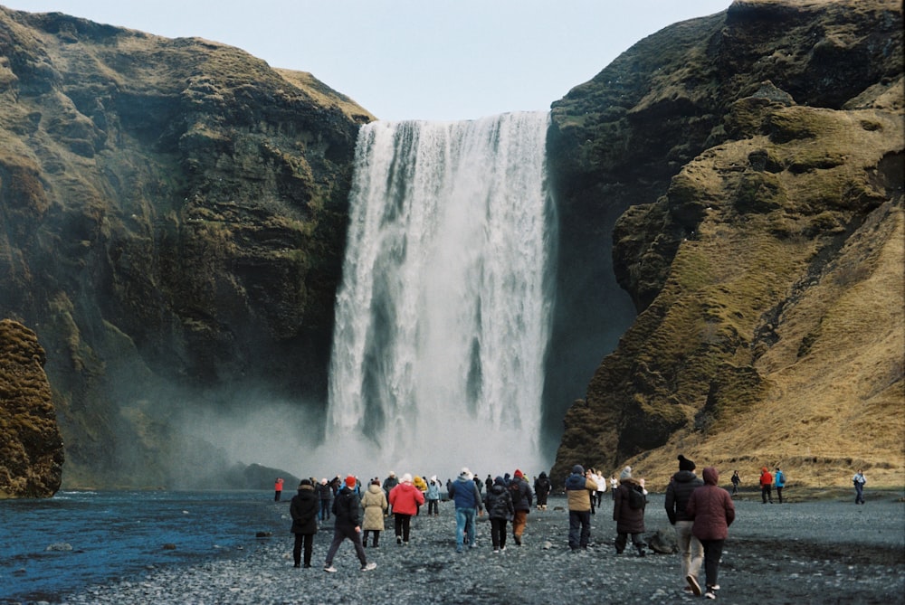 a group of people standing in front of a waterfall