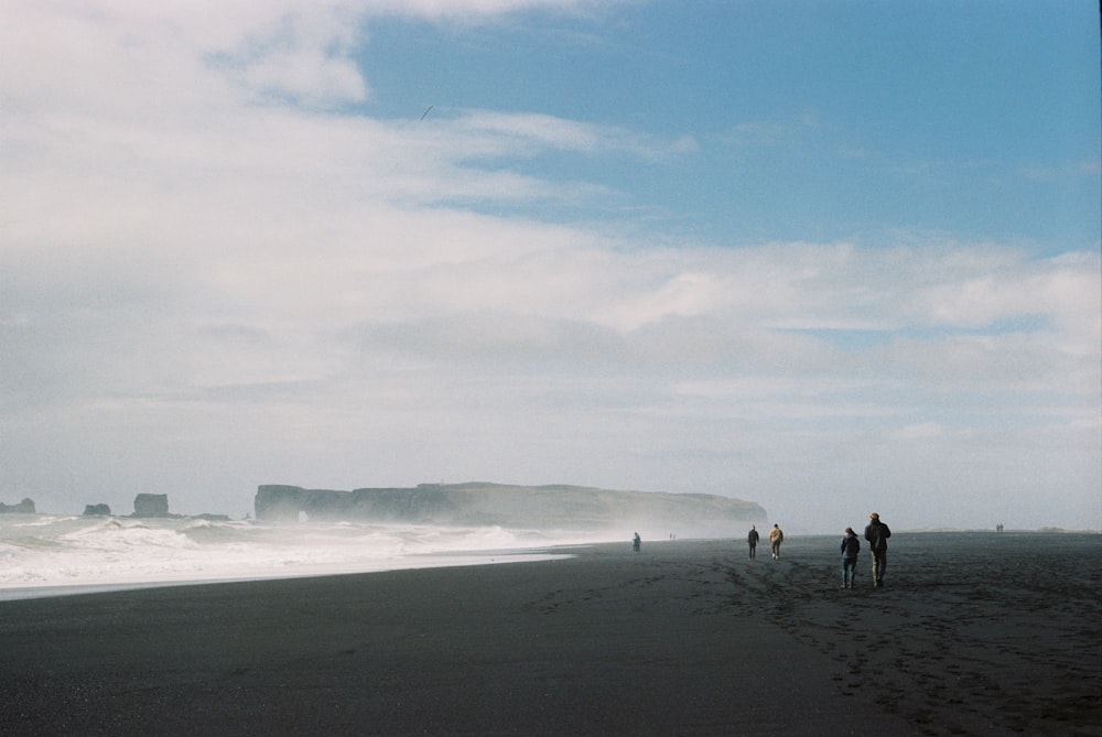 a group of people standing on top of a sandy beach