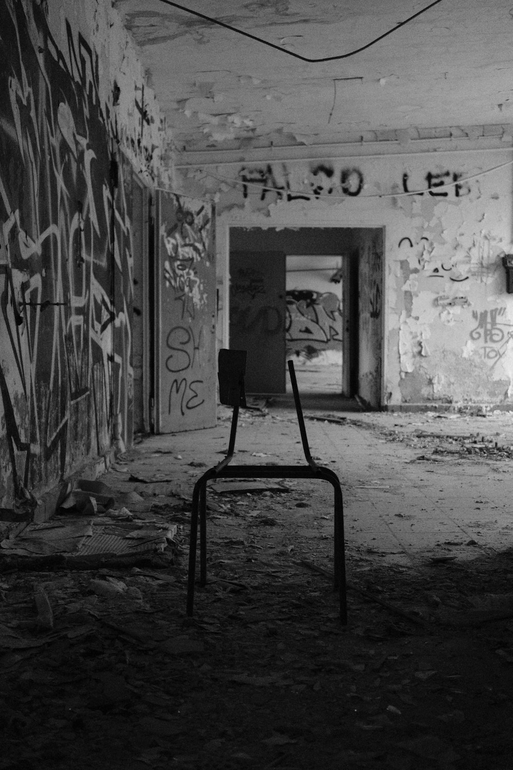 a black and white photo of a chair in an abandoned building