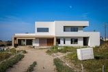 a large white house sitting on top of a dirt road