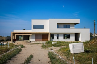 a large white house sitting on top of a dirt road