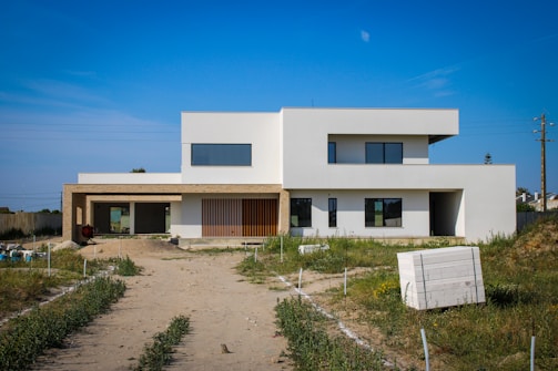 a large white house sitting on top of a dirt road