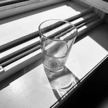 Close-up of a crystal-clear glass filled from an Aquavita purifier on a sunny windowsill.