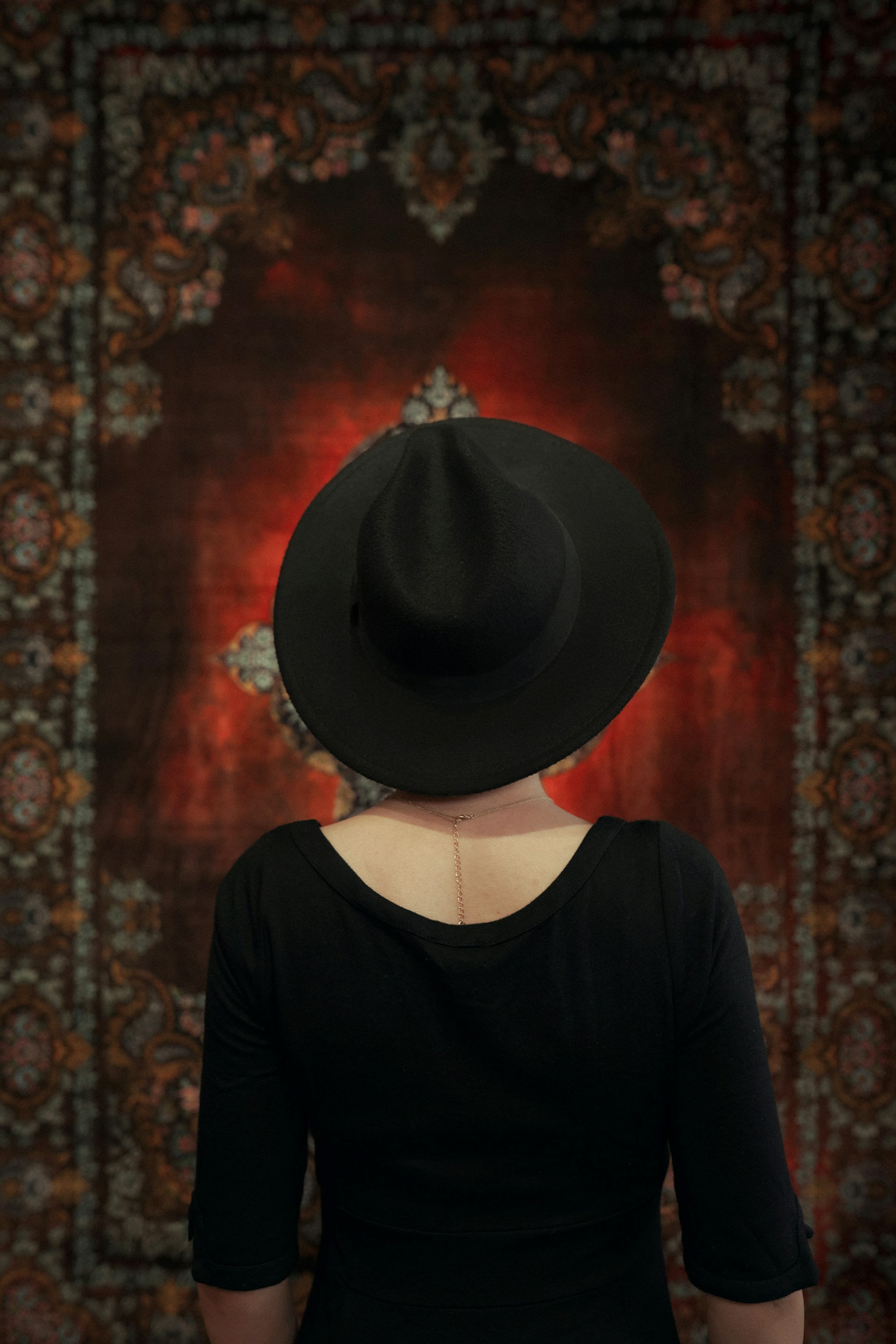 a woman wearing a black hat in front of a rug