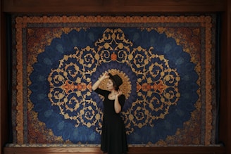 a woman standing in front of a blue and gold wall