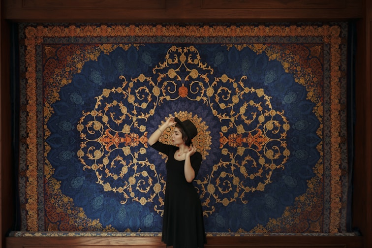 a woman standing in front of a blue and gold wall