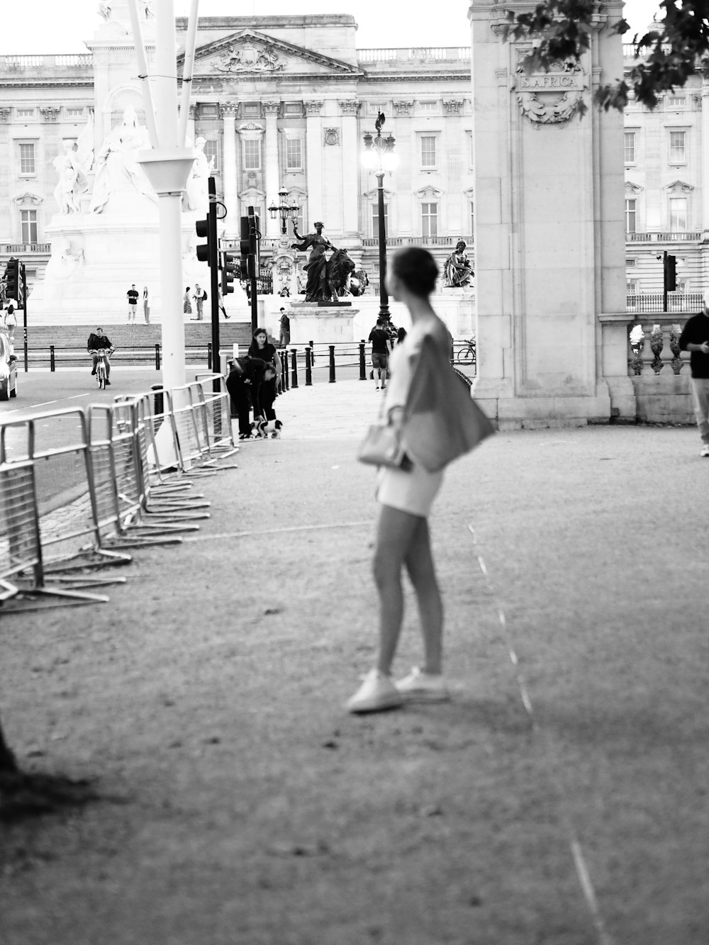 a woman walking down a street next to a fence