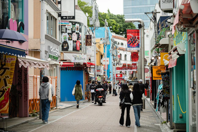 A bustling city street with people walking and bright storefronts.