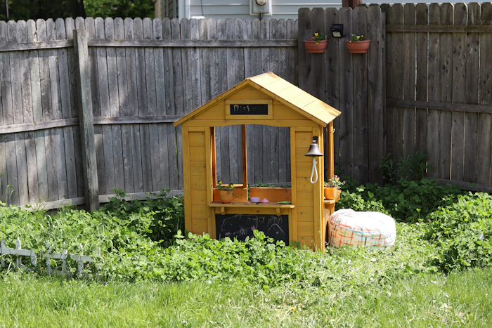 Kids' wooden playhouse in front of a weathered privacy fence