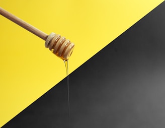 Raw honey drizzled over a wooden honey dipper.