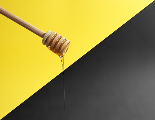 Raw honey drizzled over a wooden honey dipper.