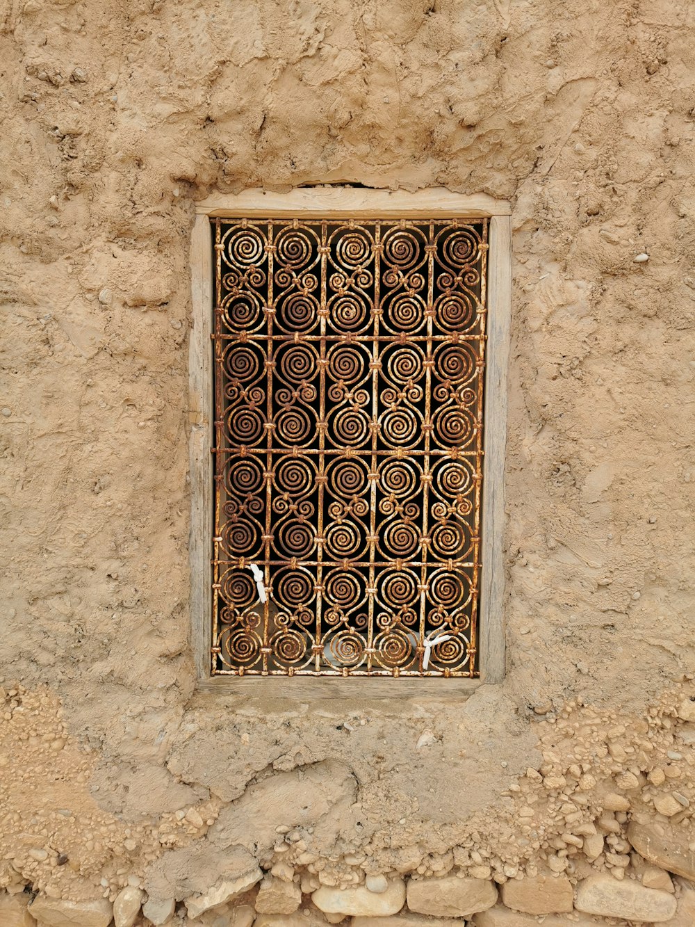 a window in a stone wall with a metal grate