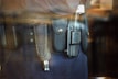 A close-up view of a police or security officer's duty belt equipped with various gear including a baton, a radio, and handcuffs. The equipment is secured in pouches and holsters on a dark-colored fabric belt.