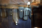 A close-up view of a police or security officer's duty belt equipped with various gear including a baton, a radio, and handcuffs. The equipment is secured in pouches and holsters on a dark-colored fabric belt.