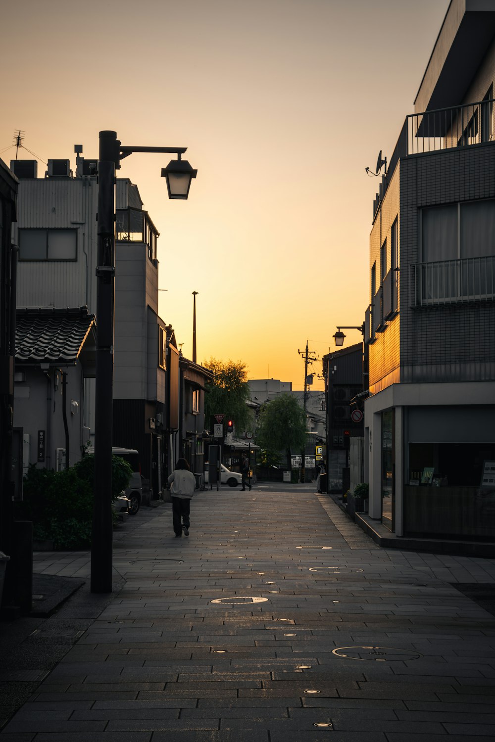 a person walking down a street at sunset