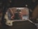 A rectangular rear-view mirror shows a reflection of a person holding a camera. The mirror has dust and smudges on its surface, and the background is a bit blurry with indistinguishable objects.