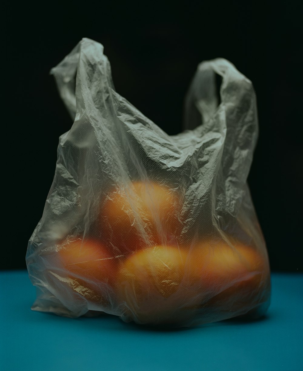 a plastic bag filled with oranges on a blue surface