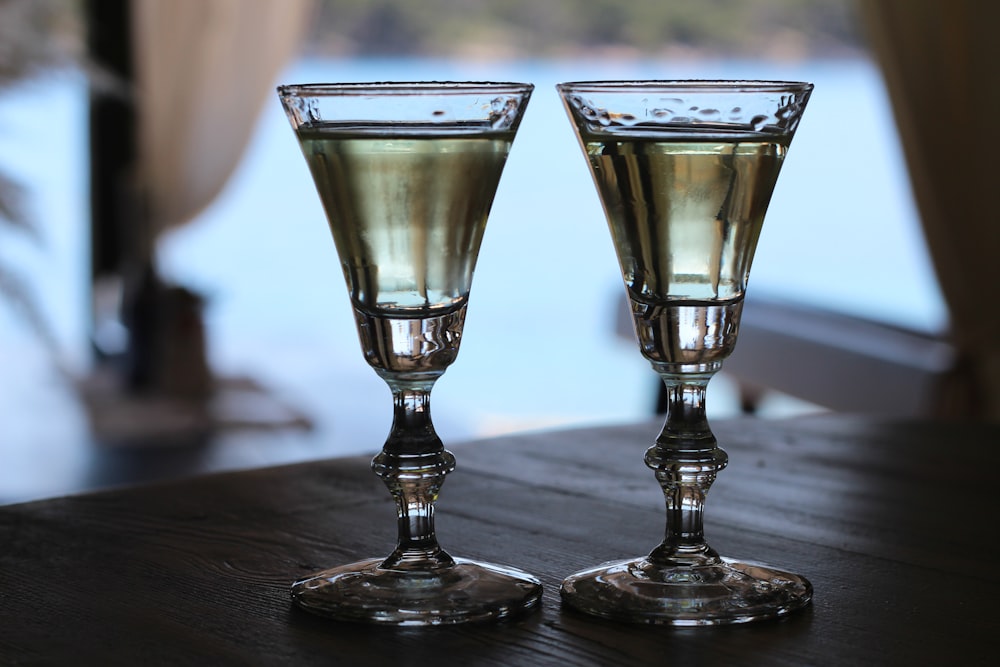 a couple of wine glasses sitting on top of a wooden table