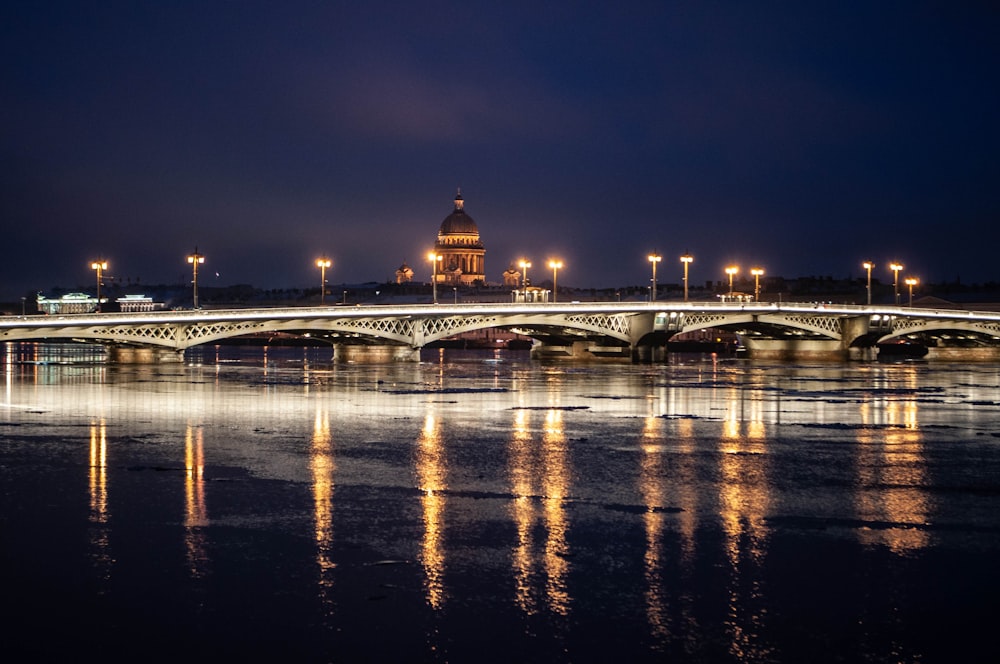 a bridge over a body of water with a clock tower in the background