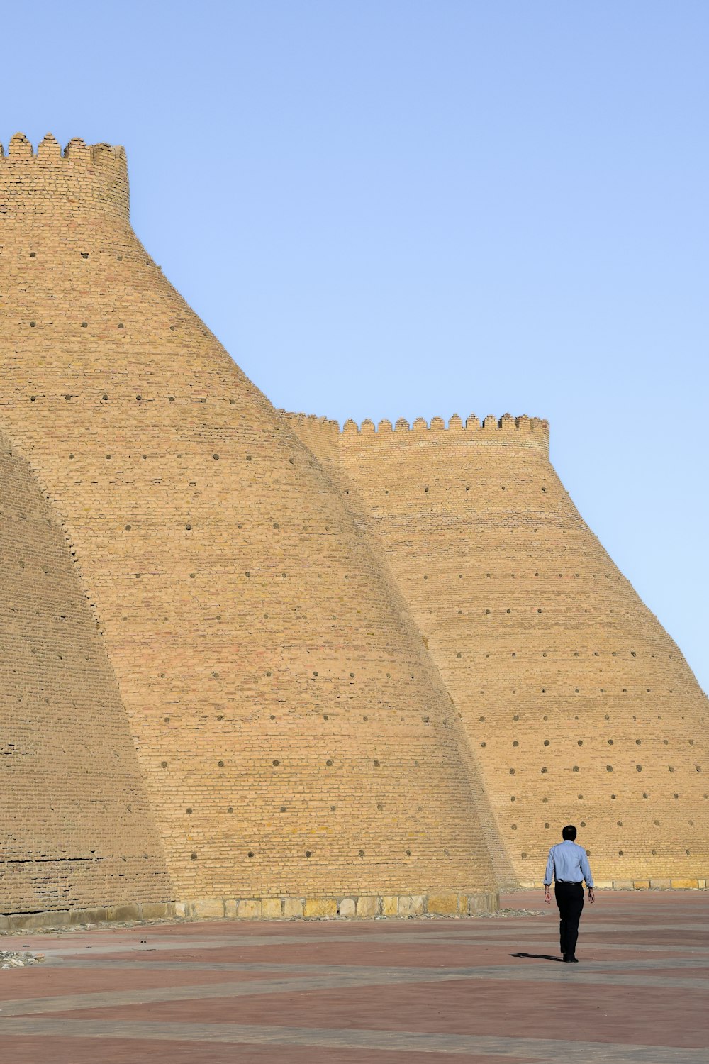 a man walking in front of a large wall