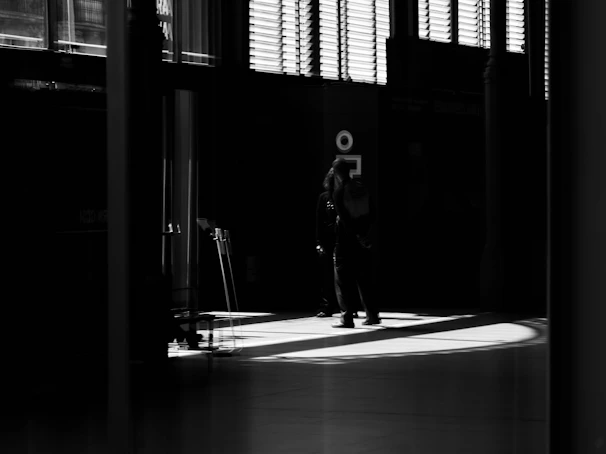 A cinematic frame showing a powerful moment between two characters in a dimly lit room.