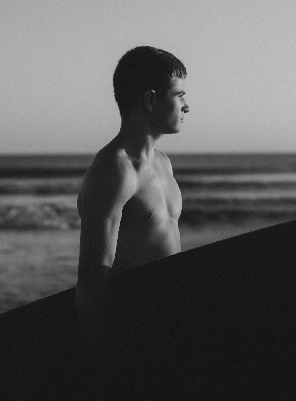 a black and white photo of a man holding a surfboard