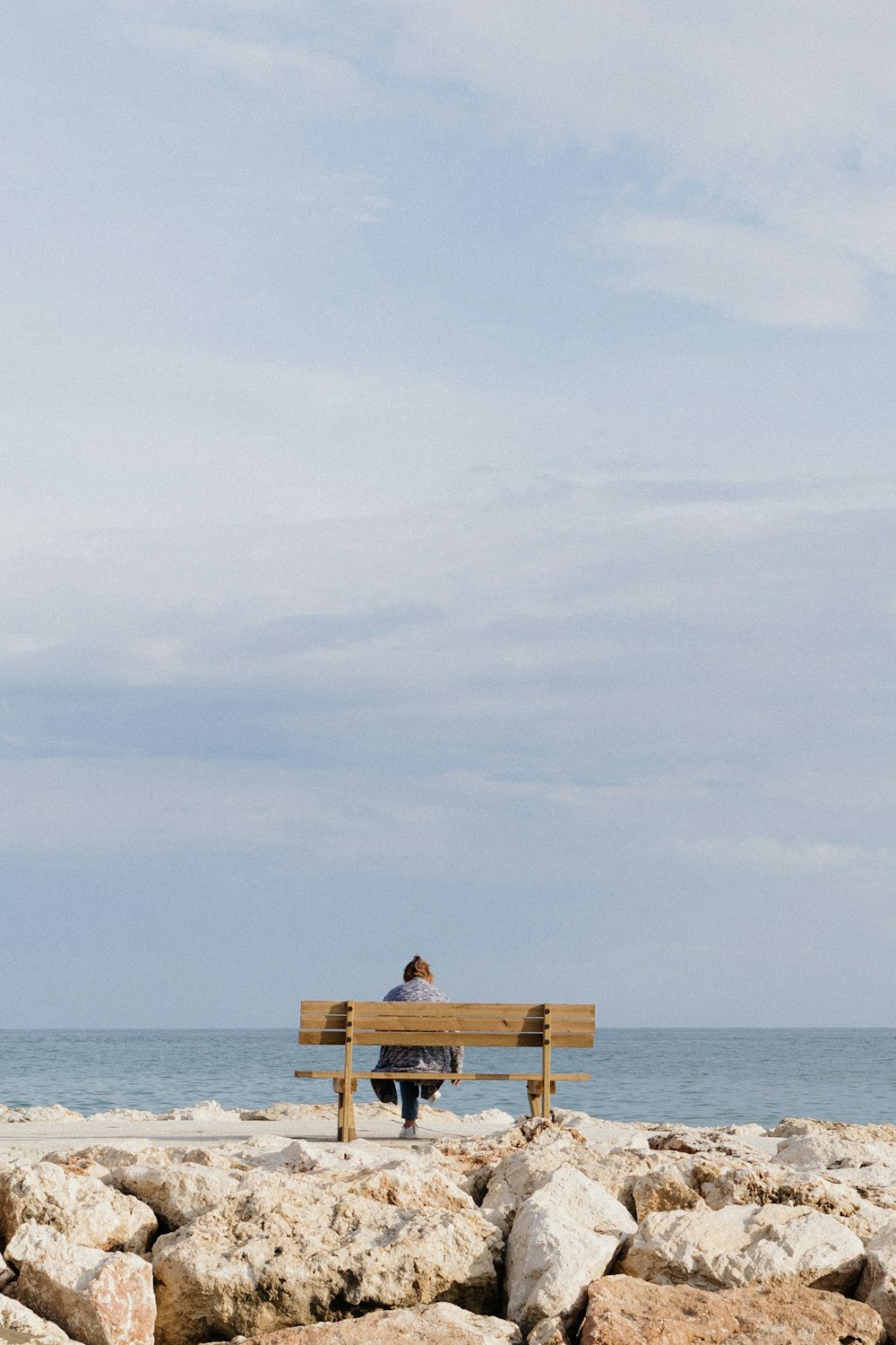 a man sitting on a bench on a rocky beach