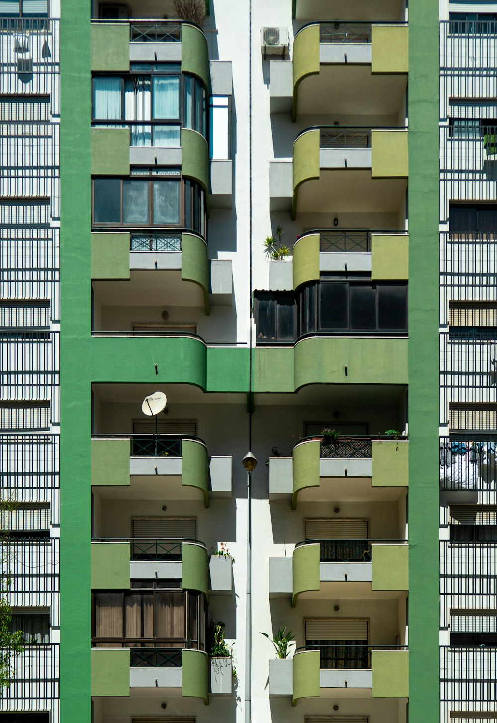 a tall green and white building with balconies