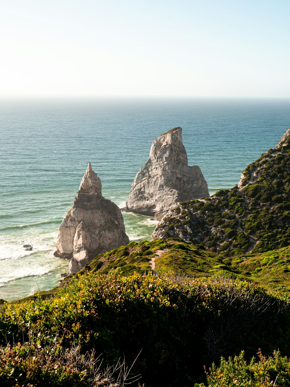 a couple of large rocks sitting on top of a lush green hillside