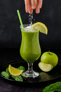 Healthy smoothie being poured into a glass with seh enhancer bottle in the background