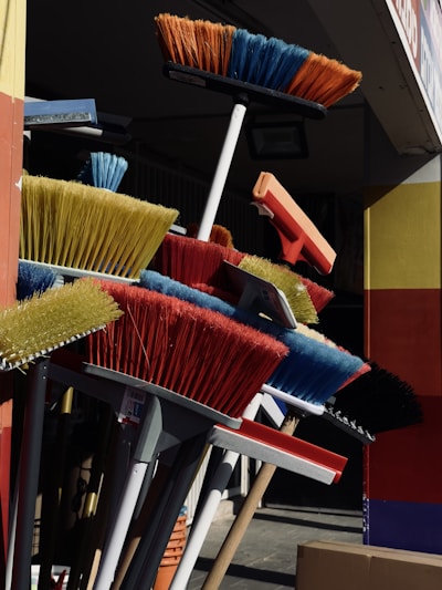 A colorful display of various mops and brooms neatly arranged in a bright, clean showroom.