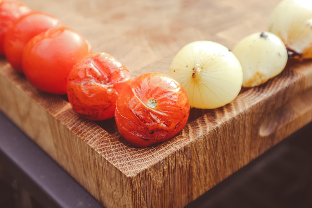 a wooden cutting board topped with tomatoes and onions