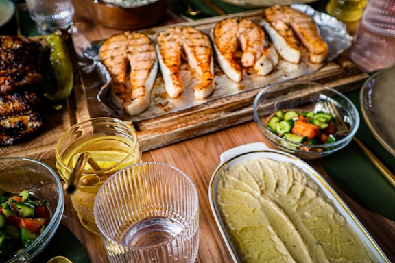 A colorful spread of dishes including a burger, salad, pizza, and salmon on a rustic wooden table