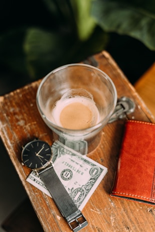 An elegant leather wallet displayed next to a cup of coffee and a notebook.