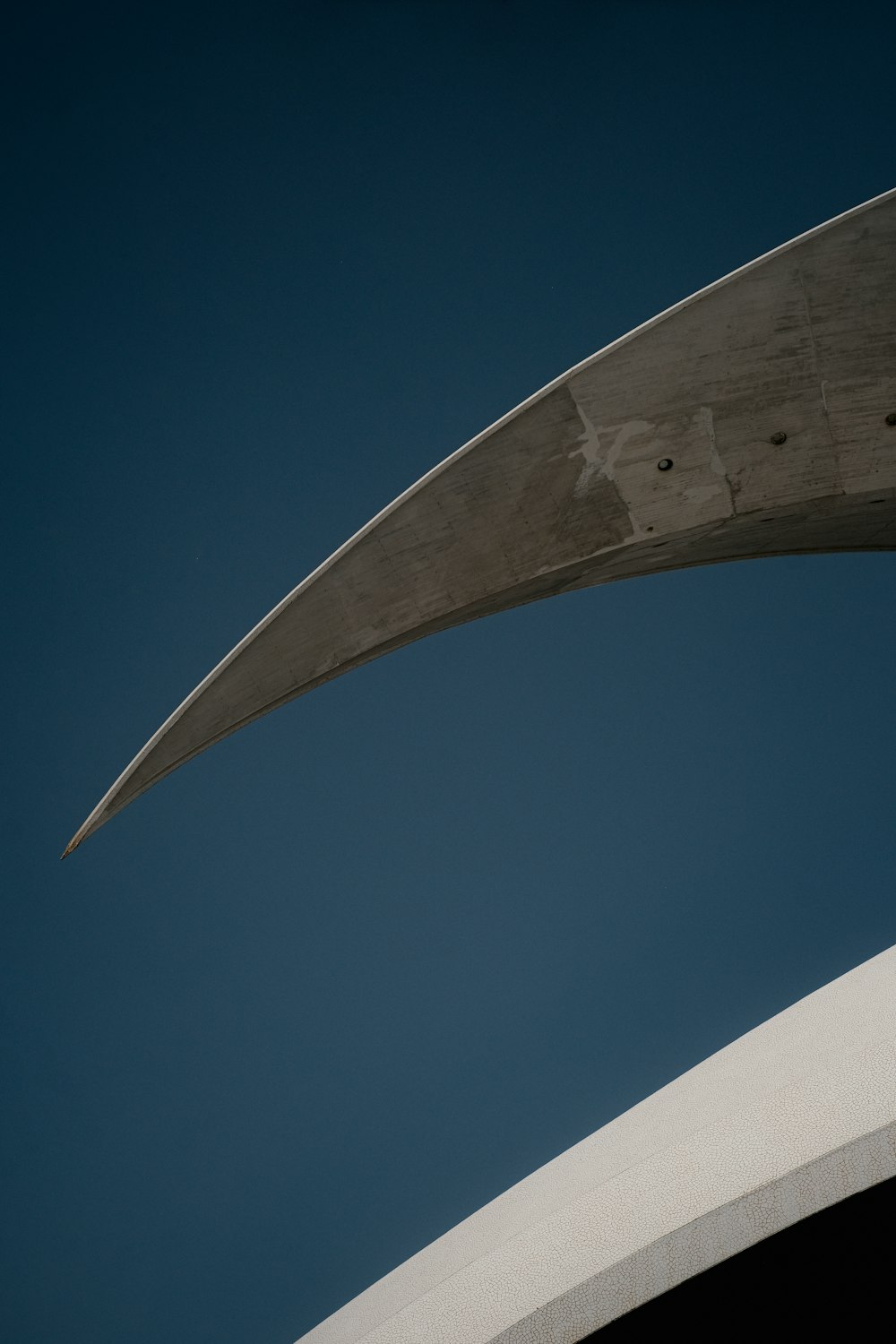 Una estructura curva de hormigón con un cielo azul en el fondo