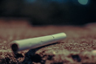 A close-up of a broken cigarette lying on a wooden table.