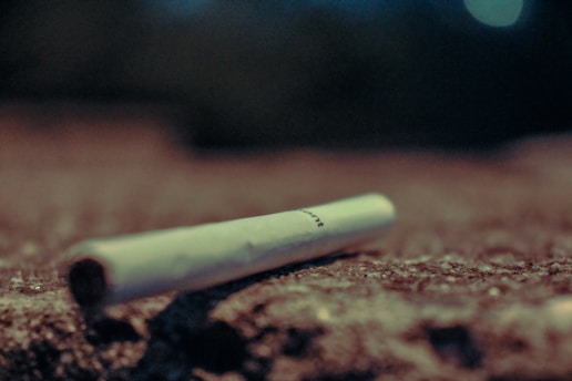 A close-up of a broken cigarette lying on a wooden table.