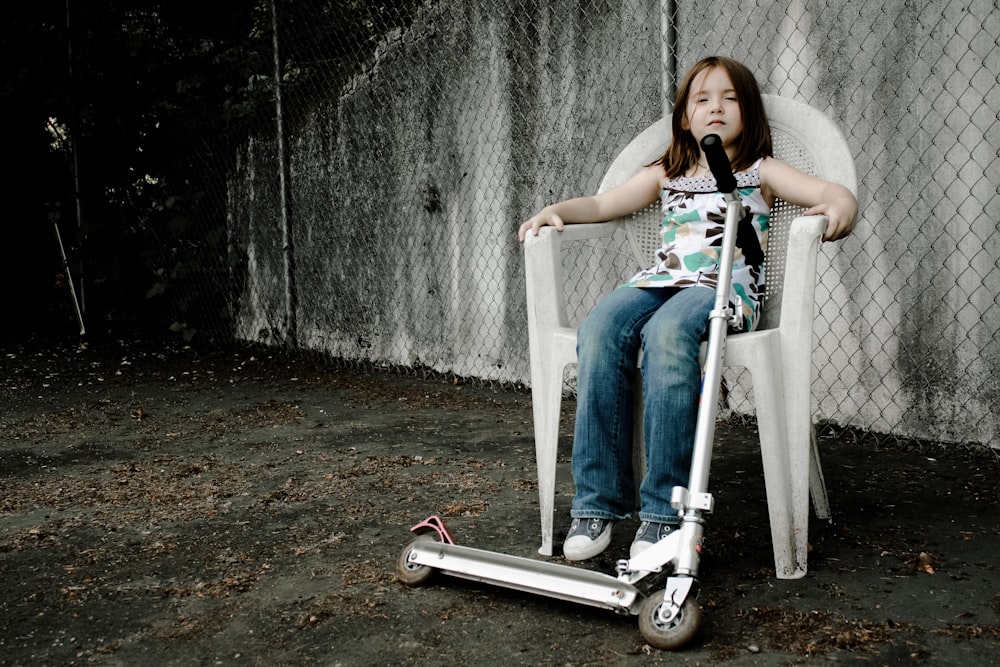 a little girl sitting in a chair on a scooter