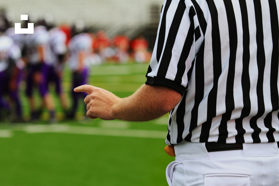 Man Ref A referee standing on a football field with a group of people in the ...