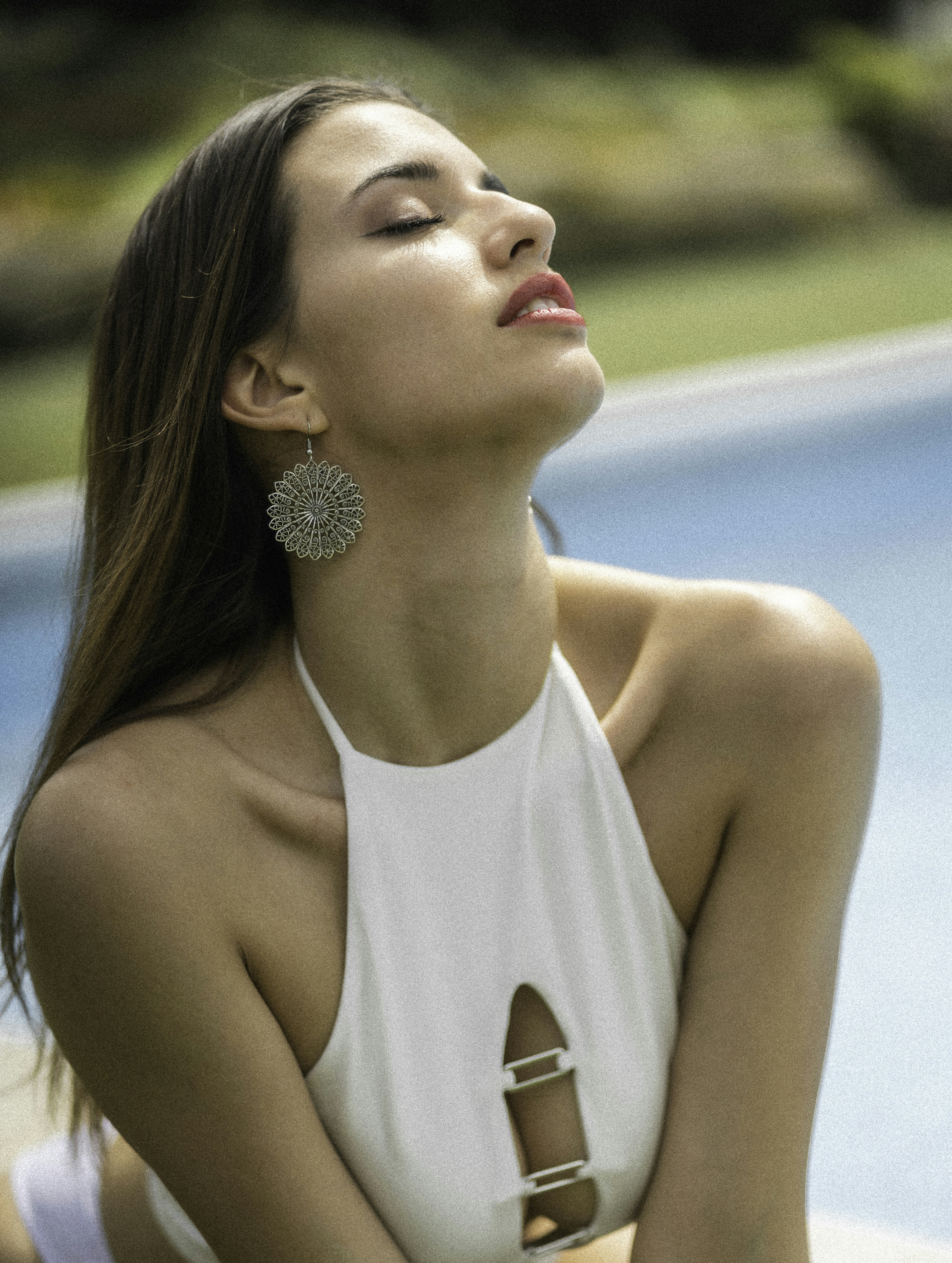 a woman in a white top sitting next to a pool