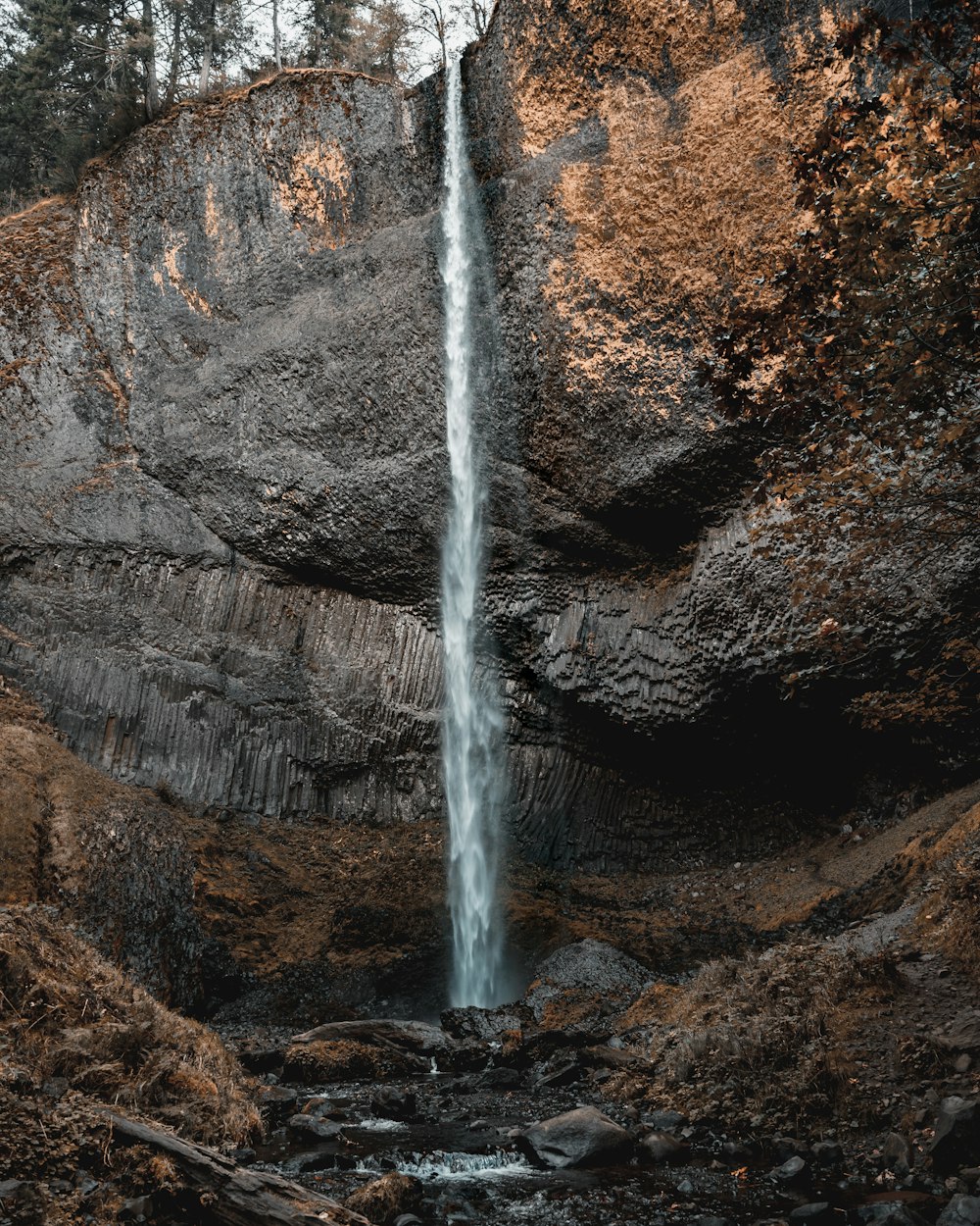 a tall waterfall in the middle of a forest